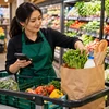 Сотрудник супермаркета собирает свежие продукты в пакет для онлайн-заказа